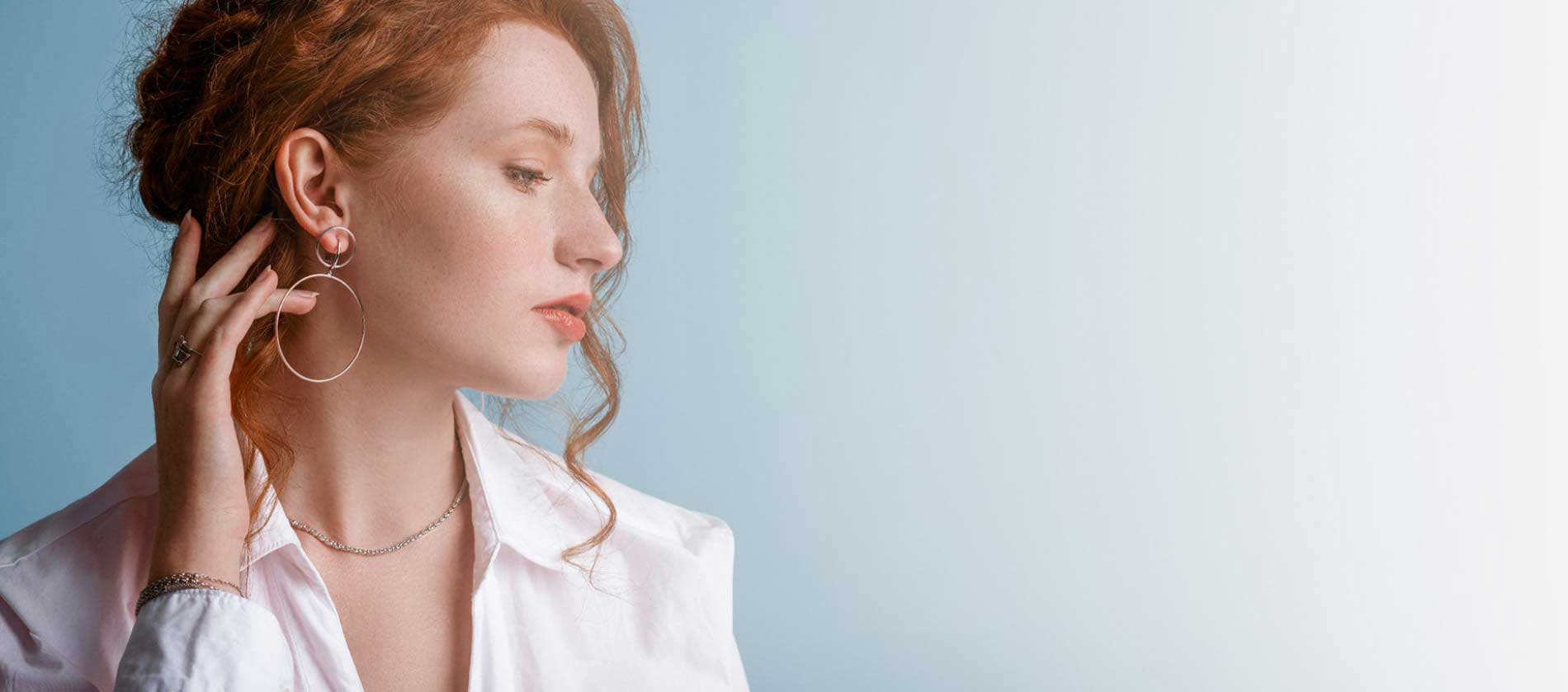 Mujer de perfil con pendientes y cadena de Joyería Sarang, imagen representativa de la marca